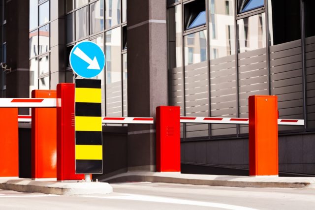 Parking entrance with barrier and mandatory way sign, building in background